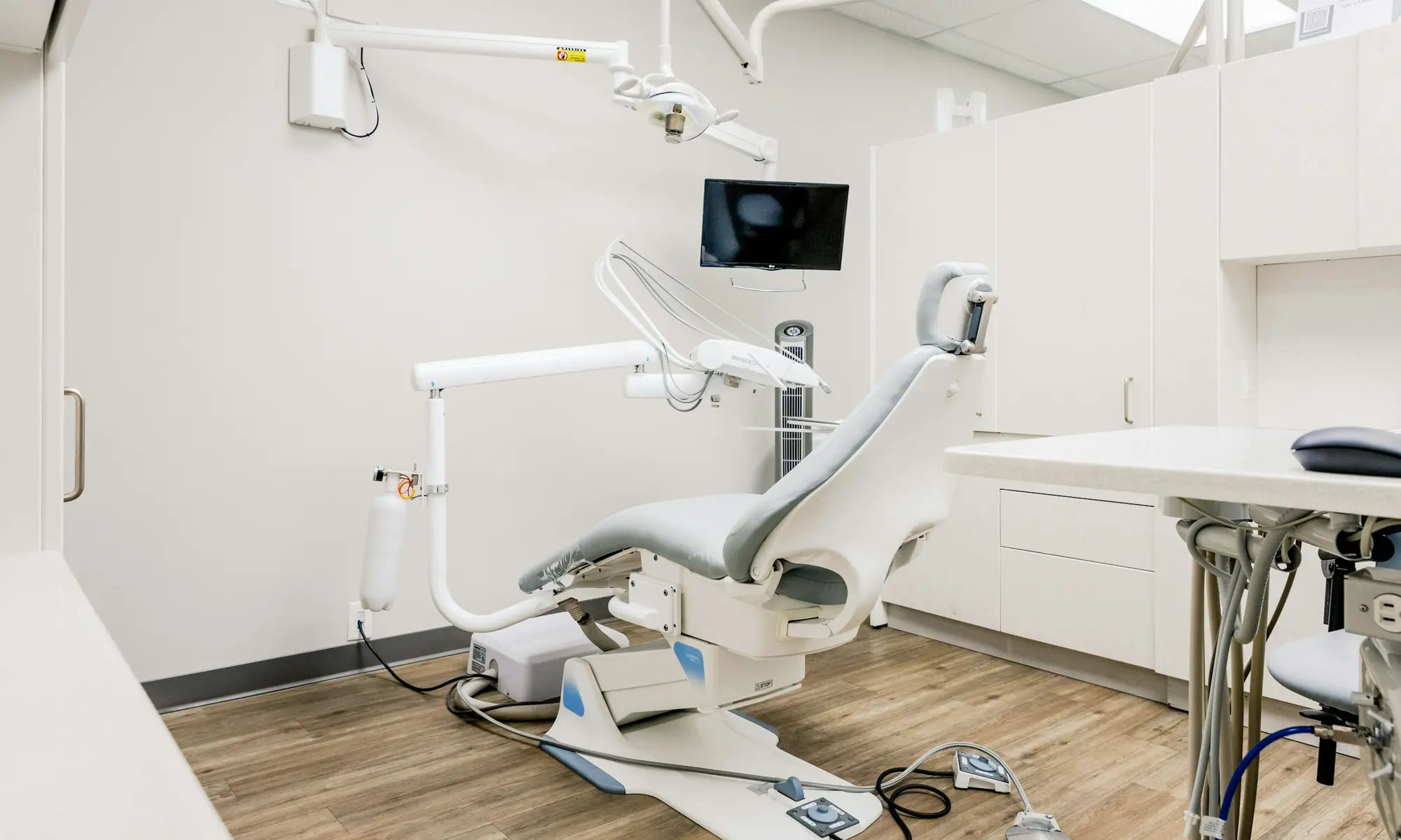 Ruang perawatan klinik gigi dengan kursi dental dan lampu pemeriksaan